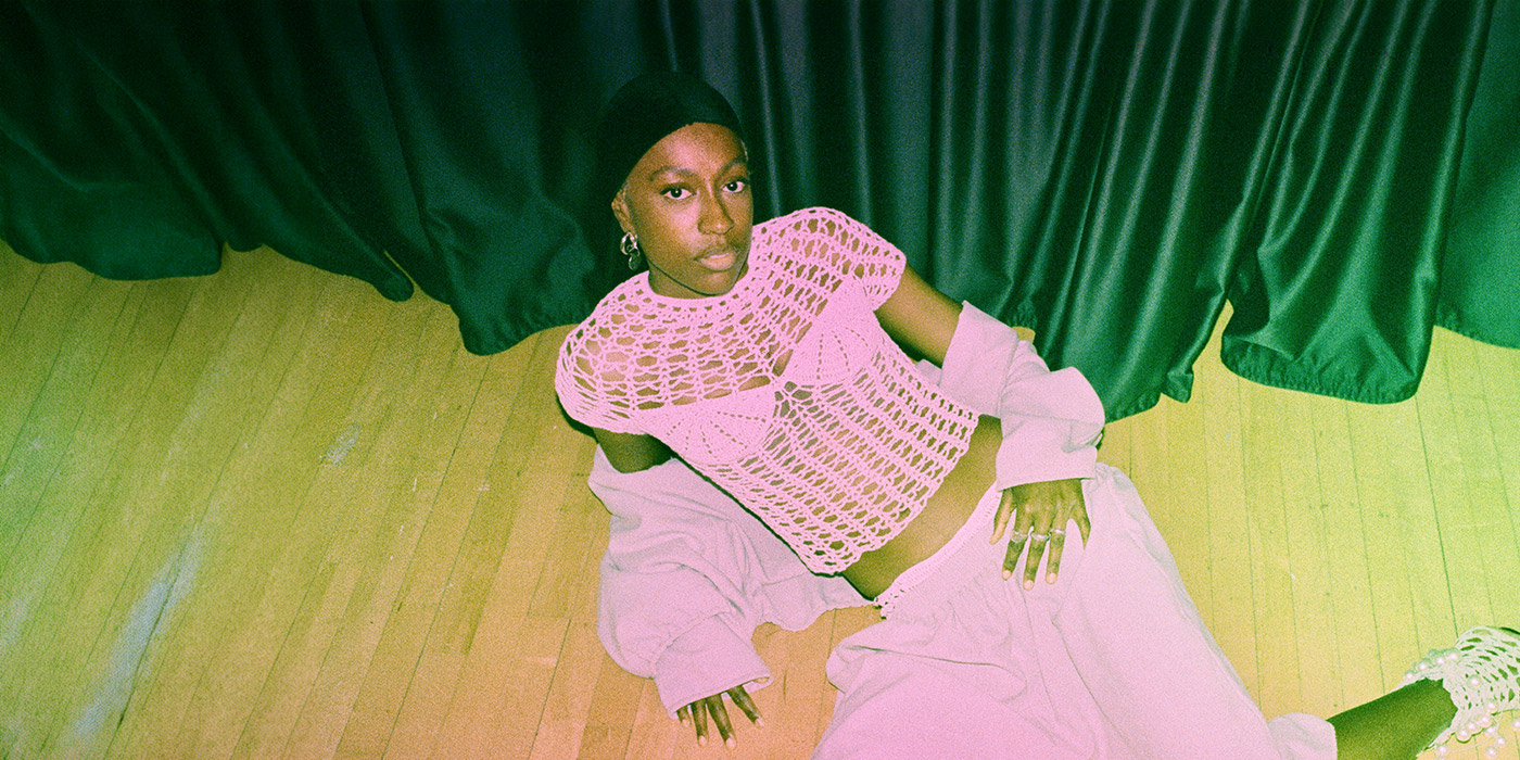 the perspective is from above: anaiis laying on the floor posing in a pink costume with a net shirt. 